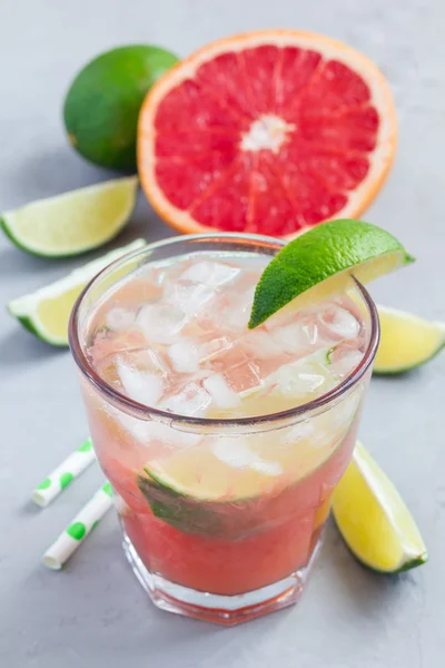 Kall rosa cocktail med färsk grapefrukt, lime och is, vertikal — Stockfoto