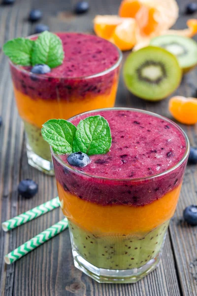 Trippel smoothie i glas: kiwi-mint, mandarin-aprikos och jordgubb-blåbär — Stockfoto