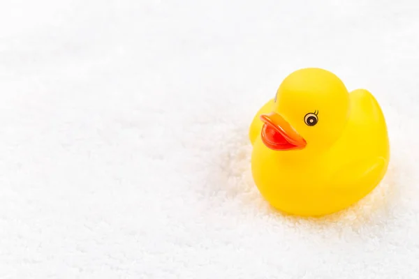 One rubber duck on a white terry bath towel, place for copy space, horizontal, closeup