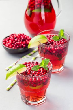 Lingonberry ve limonlu punç veya bardakta limonata ve gri arka planda sürahi, dikey