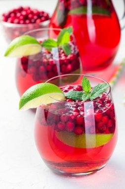 Lingonberry ve limonlu punç veya cam içinde limonata ve gri arka planda sürahi, dikey