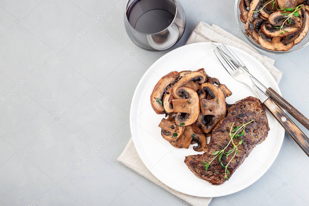 Beef steak with sauteed brown mushrooms and thyme, on a gray background, horizontal, top view, copy space