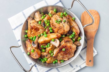 Patatesli, mantarlı ve yeşil bezelyeli tavuk, metal bir tencerede, yatay, üst manzara, yakın çekim