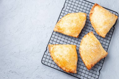 Ev yapımı küçük şeftali ve tarçınlı el turtası. Hamur hamuru, şeker serpiştirilmiş. Soğutma rafına serpiştirilmiş.