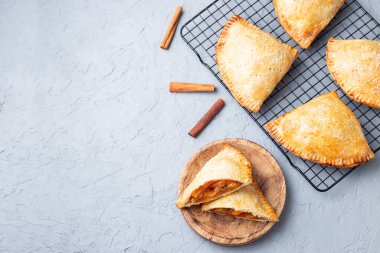 Küçük şeftali ve tarçınlı, hamur hamurlu el pastaları, şeker serpilmiş, ahşap bir tabakta ve soğutma rafında, üst görünümde, yatay, kopyalama alanı