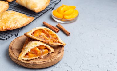 Küçük şeftali ve tarçınlı, hamur hamurlu, şeker serpilmiş, ahşap tabakta ve soğutma rafında, yatay, kopyalama alanı