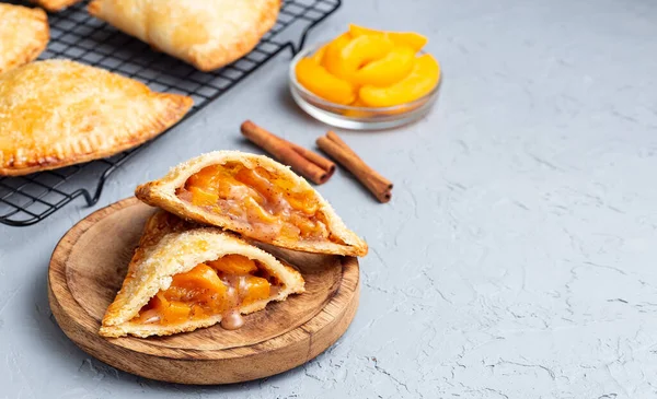 Küçük şeftali ve tarçınlı, hamur hamurlu, şeker serpilmiş, ahşap tabakta ve soğutma rafında, yatay, kopyalama alanı