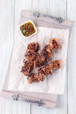 Biftek şişleri ve chimichurri sosu, ahşap tepside, dikey, üst görünümde.