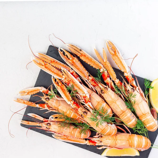 Sea crayfishes on a stone plate served with dill and lemon, top view, copy space, square format