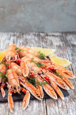 Sea crayfishes on a stone plate served with dill and lemon, vertical, copy space