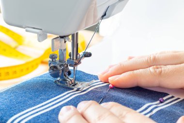 Kadın elleri çizgili mavi kumaş ve dikiş makinesinde, el işi ya da hobi, yatay, yakın çekim