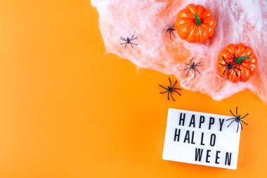 Portakallı Cadılar Bayramı arka planı örümcekler, balkabağı ve ışık kutusu, yatay, üstten görünüm, kopyalama alanı