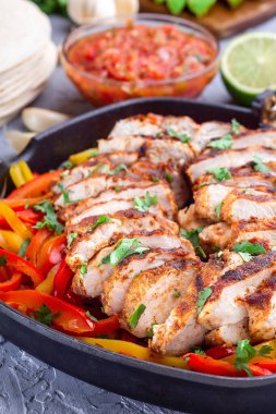 Tavada dolmalık biber ve soğanlı tavuk Fajitas, salsa Asada, ekşi krema, avokado ve tortilla, Güneybatı Tex-Mex Mutfağı, dikey, yakın çekim