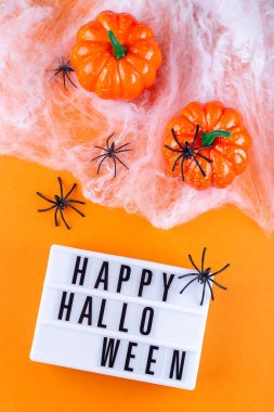 Cadılar Bayramı arkaplanı ağ örümcekler, balkabağı ve ışık kutusu, dikey, üst görünüm