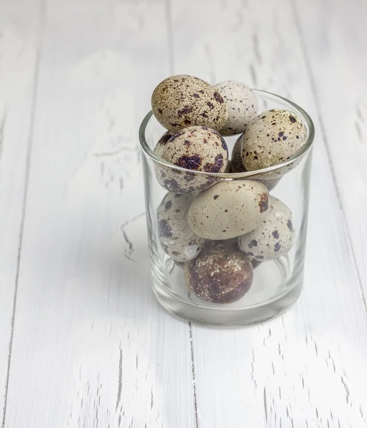 Много пятнистых перепелиных яиц в стекле на деревянном столе — стоковое фото