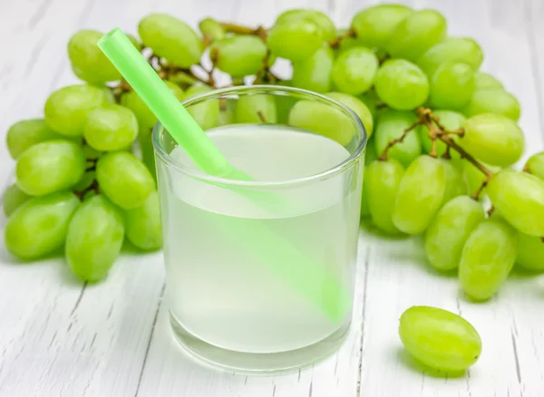 Copo de suco de uvas brancas e uvas no fundo — Fotografia de Stock