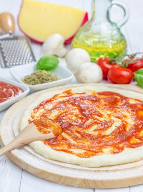 Pizza hamur bir ahşap tahta üzerinde domates soslu