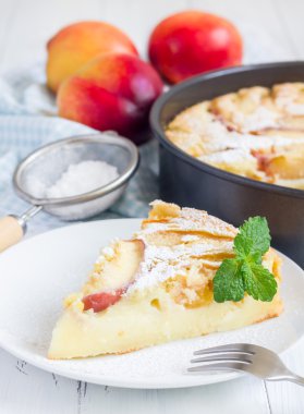 Slice of peach clafoutis on a white plate