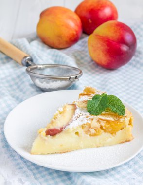 Slice of peach clafoutis on a white plate
