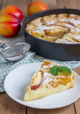 Slice of peach clafoutis on a white plate
