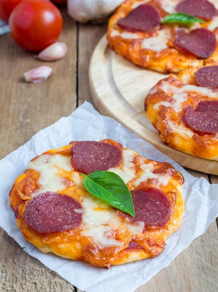 Mini pizza al salame piccante fatta in casa su una tavola di legno — Foto Stock