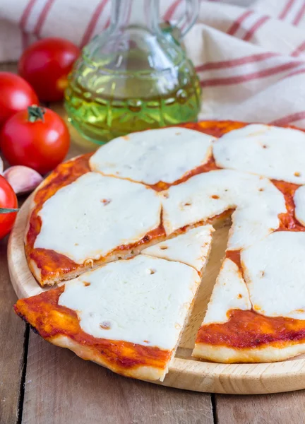 Homemade pizza with mozzarella cheese on a wooden board — Stockfoto