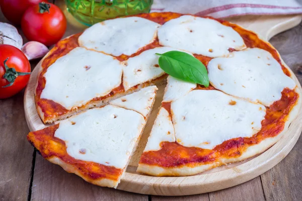 Homemade pizza with mozzarella cheese on a wooden board — Stockfoto