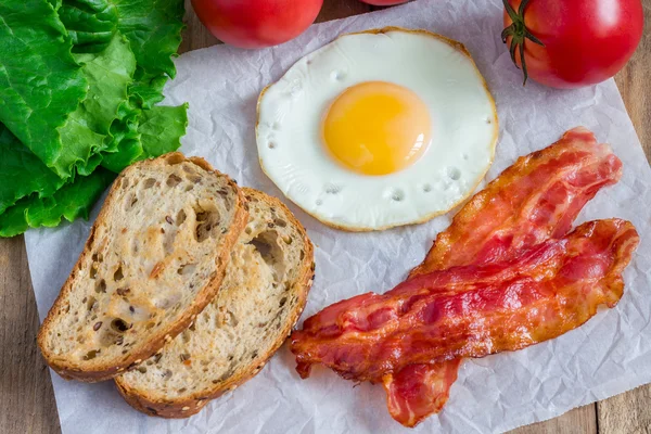 Сэндвич с открытым лицом с яйцом, беконом, помидорами и салатом — стоковое фото