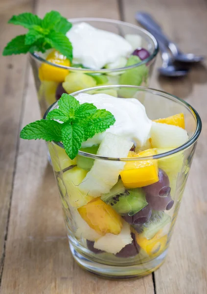 Fresh healthy fruit salad in a glass with whipping cream on top — Stock Photo, Image