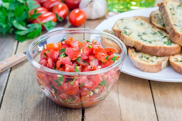Maken van tomaat bruschetta - knoflook kaas crostini en gehakte tomaten met kruiden — Stockfoto