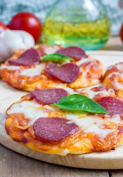 Mini pizza al salame piccante fatta in casa su una tavola di legno — Foto Stock