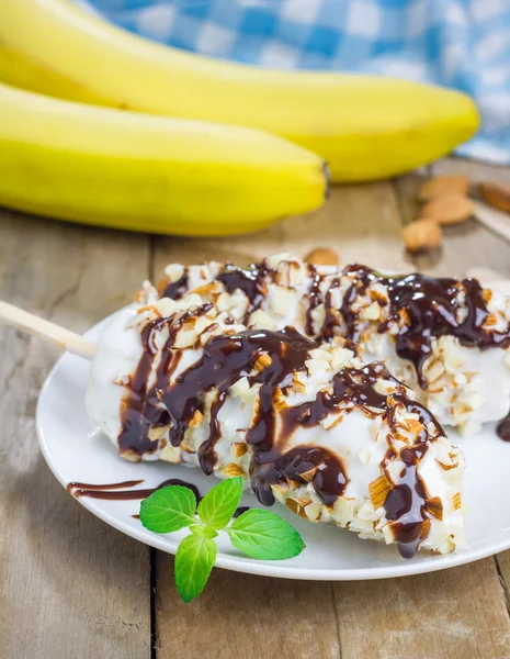 Frozen banana covered with yogurt, almonds and chocolate syrup