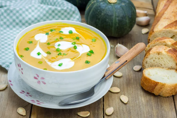 Pumpkin soup with sour cream on a wooden table — Stock Photo, Image