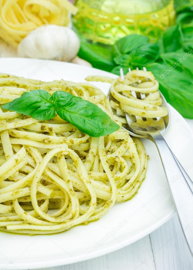 Tagliatelle pasta with pesto sauce on a white plate