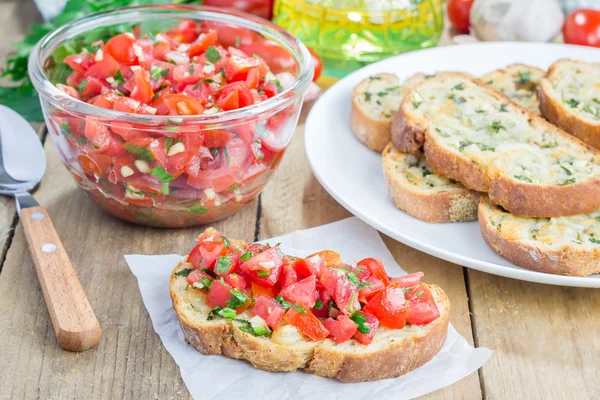 Bruschetta z pomidorami, ziołami i oleju na Pieczywo czosnkowe tosty ser — Zdjęcie stockowe
