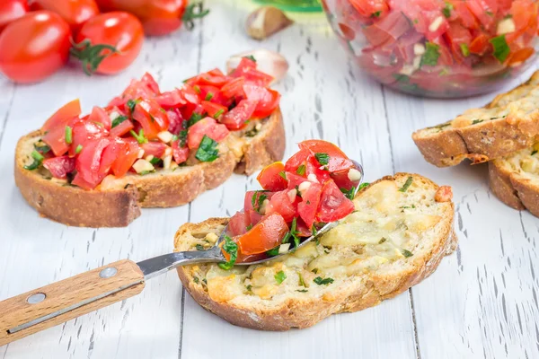 Bruschetta con pomodori, erbe aromatiche e olio su pane tostato all'aglio — Foto Stock