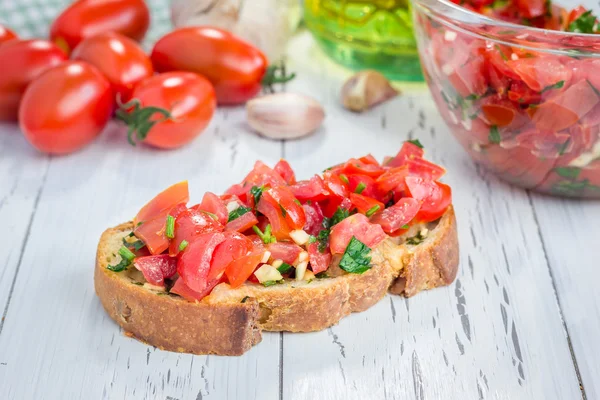 Bruschetta z pomidorami, ziołami i oleju na Pieczywo czosnkowe tosty ser — Zdjęcie stockowe