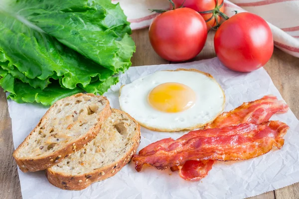 Efectuarea sandwich-ului deschis cu ou, slănină, roșii și salată verde — Fotografie, imagine de stoc