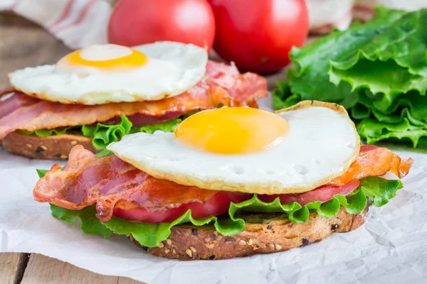 Sandwich deschis cu ou, slănină, roșii și salată verde — Fotografie, imagine de stoc