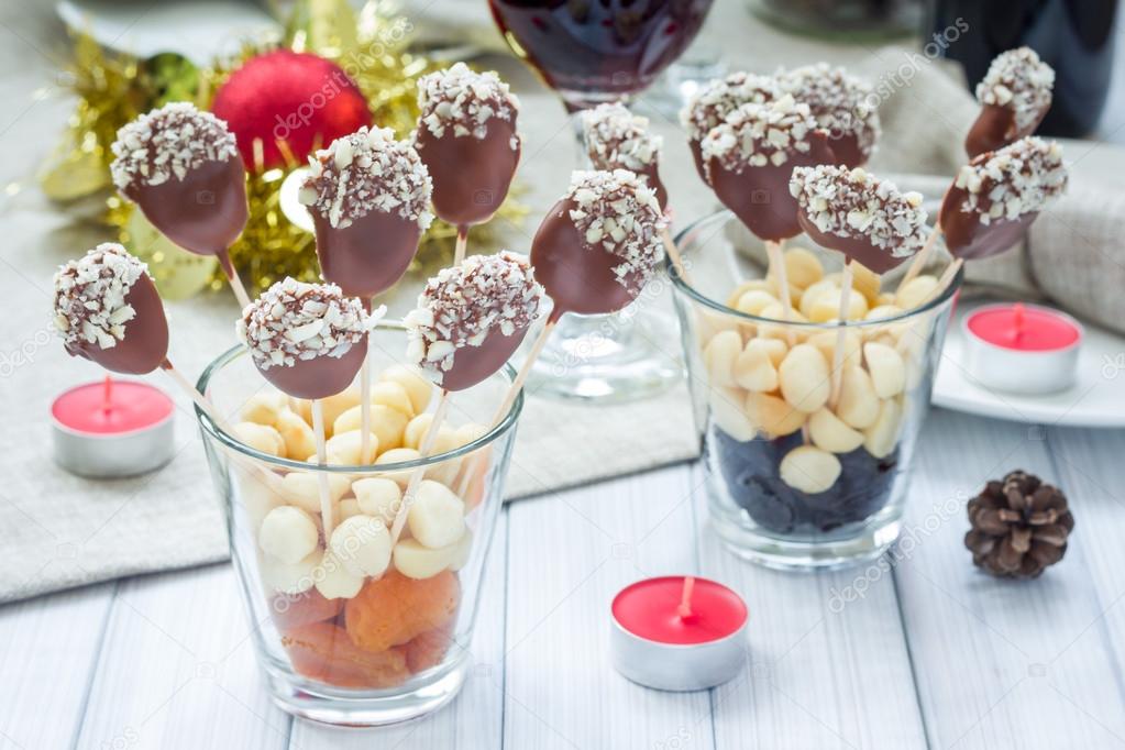 Homemade apricot and prunes lollipops, covered with chocolate and macadamia nuts