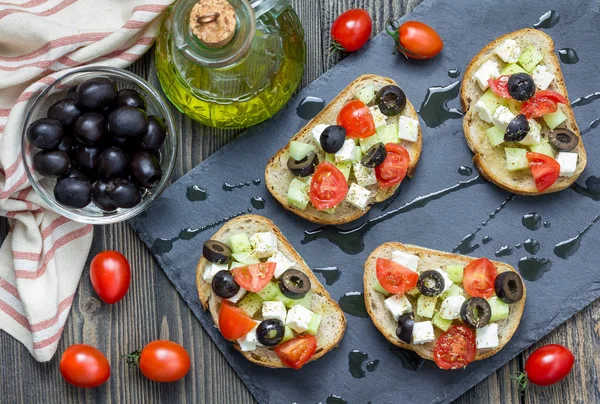 Греческий стиль кростини с сыром фета, помидоры, огурец, оливки и травы, вид сверху — стоковое фото