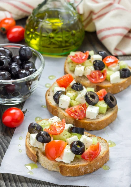 Кростини в греческом стиле с сыром фета, помидорами, огурцом, оливками и травами — стоковое фото