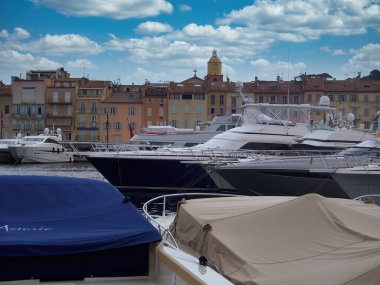 Saint Tropez, Fransa - 5. Mai 2018: Pahalı yatlarıyla limanı keşfeden Alman bir fotoğrafçı ve baharda bulutlu bir günde arka planda köyün merkezi bulunuyor.. 