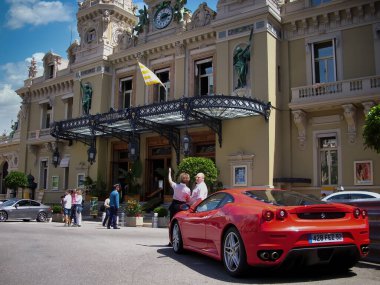 Monaco, Monte Carlo - 15 Mayıs 2018: Fransız Rivierası 'nı ziyaret eden bir Alman fotoğrafçı, bir günlük Monako gezisi, önünde pahalı arabalar olan ünlü kumarhanenin fotoğraflarını çekiyor..