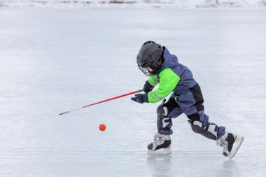 Buz pateni ve hokey oynarken küçük çocuk