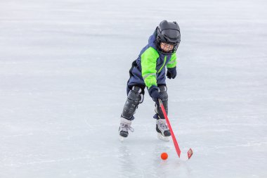 Buz pateni ve hokey oynarken küçük çocuk
