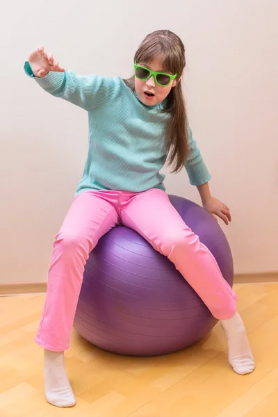 Jovem menina sentada na bola grande — Fotografia de Stock