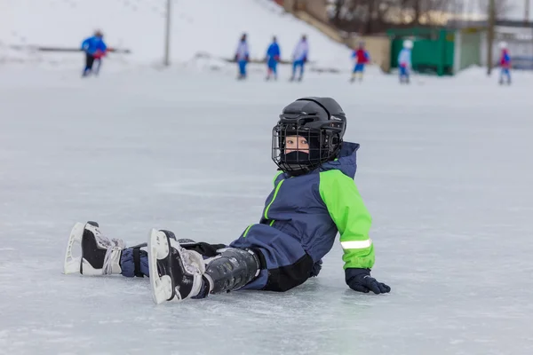 Petit garçon en patins assis sur la glace — Photo