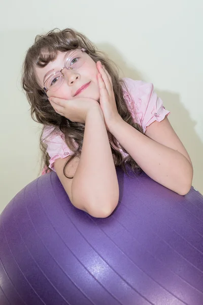 Jovem menina sentada na bola grande — Fotografia de Stock