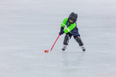 Buz pateni ve hokey oynarken küçük çocuk